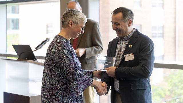 Two people shaking hands and exchanging an award